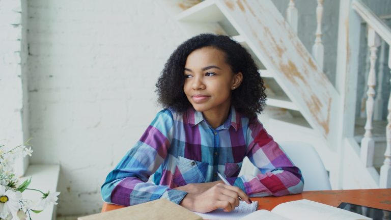 Teenage student seated at a table with an open notebook and books