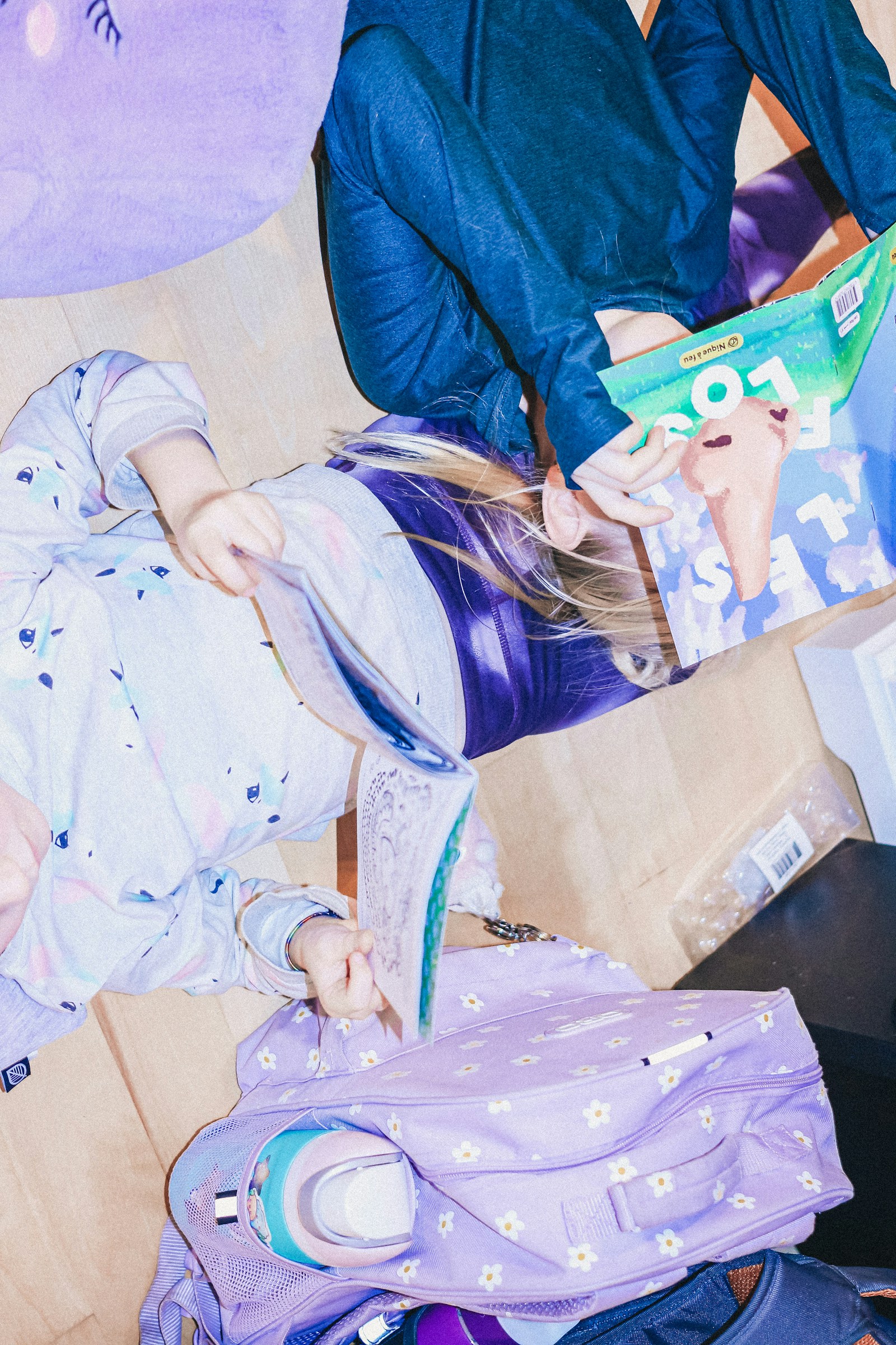 Two children looking at colourful books beside school bags