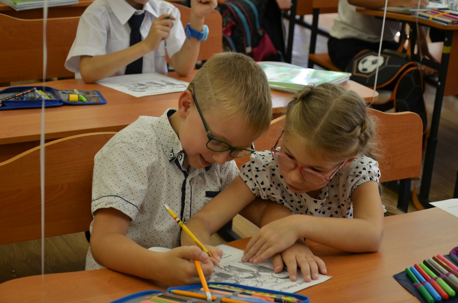 Deux enfants d’âge scolaire qui dessinent ensemble à une table de classe