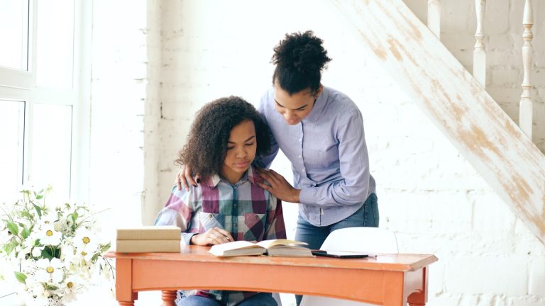 Adult supporting a teenage student working at a desk