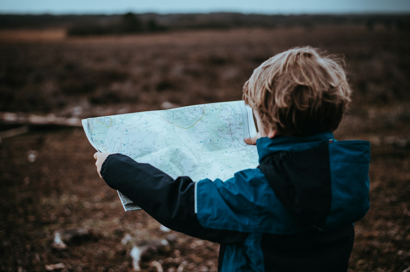 Child outdoors holding an unfolded map