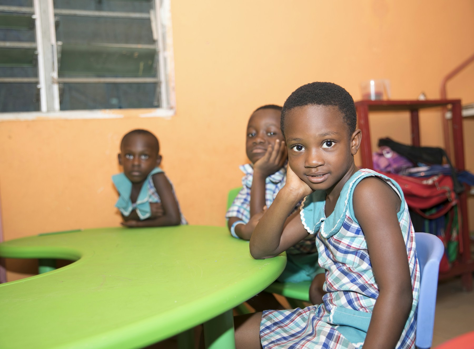 Three children seated at a classroom table